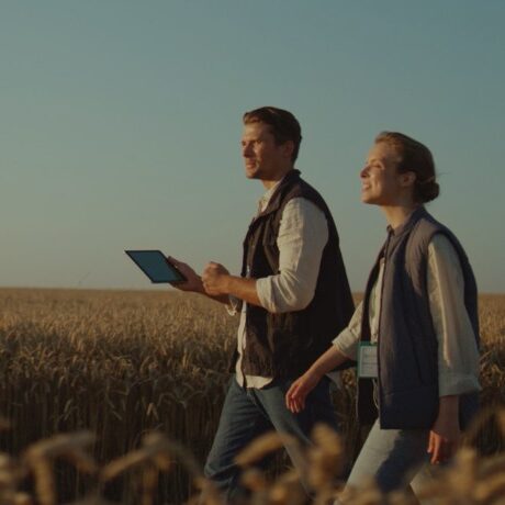 two people walking side-by-side through a field of wheat