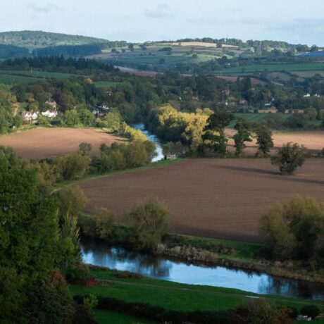river flowing through farmland valley with green trees