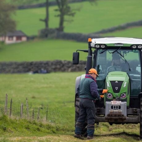 tractor in middle of field with man attending to front