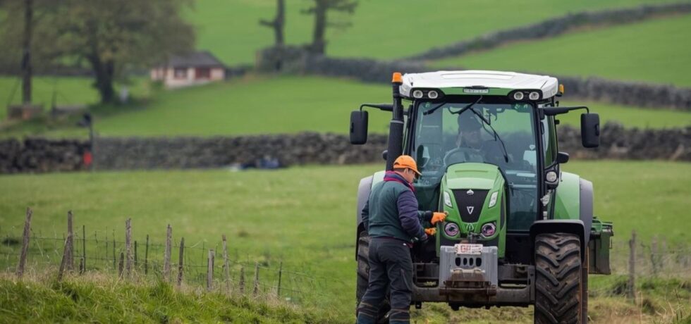 tractor in middle of field with man attending to front