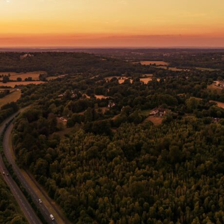 sunset over multiple farmland and forestry fields with motorway running through