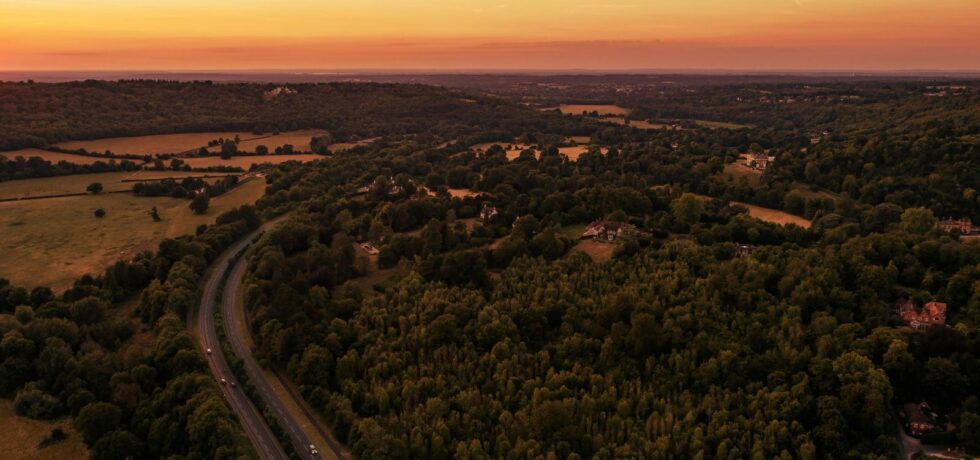 sunset over multiple farmland and forestry fields with motorway running through