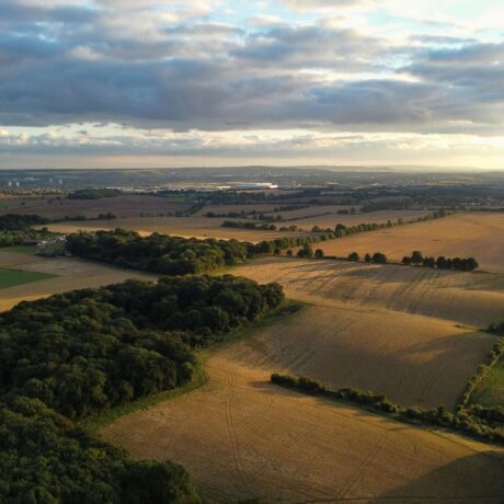 agricultural landscape with sun setting underneath clouds