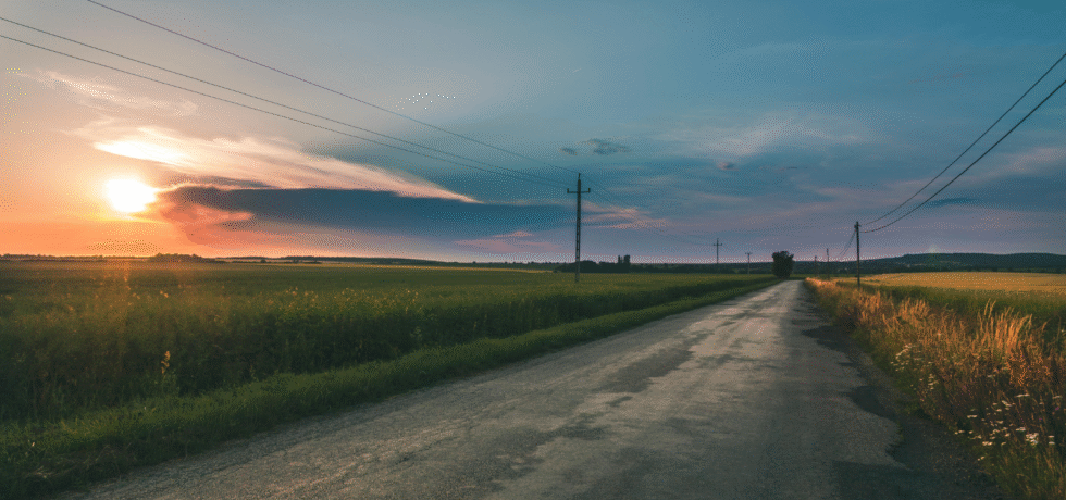 sunset on agricultural fields with road in the middle