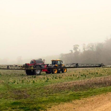 tractor spraying over field in foggy conditions