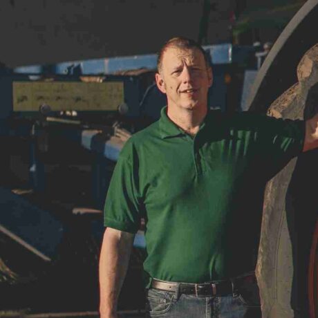 Image of a man standing next to a tractor wheel